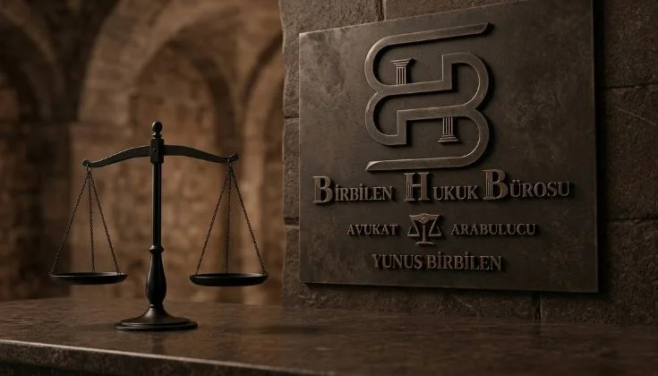 Kahverengi tonlarında bir taş üzerine oyulmuş Birbilen Hukuk Bürosu logosu ve Avukat Yunus Birbilen isimli bir levha. Yanında Bronz bir adalet terazisi